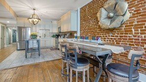 Una cucina moderna con una parete decorata in mattoni, un'isola centrale con sgabelli ed elettrodomestici in acciaio inossidabile.