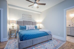 Ein Schlafzimmer mit einem Bett, zwei Nachttischen, einem Deckenventilator und einem Beistelltisch.
