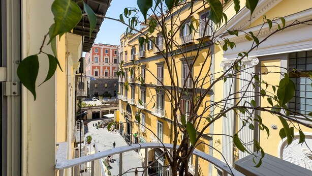 A narrow street with yellow buildings, balconies, and a tree in the foreground. - Santa Patrizia a Chiaia Apartment - Terra (Naples)