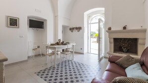 Un amplio salón con chimenea, una mesa de comedor con sillas y un televisor montado en la pared.