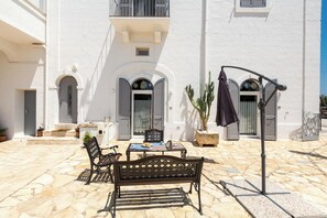Un cortile con pavimento in pietra, una panchina, un tavolo e una pianta in vaso.
