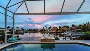 An indoor swimming pool with a view of a marina and palm trees.