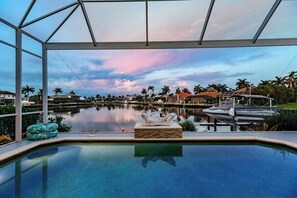 An indoor swimming pool with a view of a marina and palm trees. - Luxury Waterfront Villa with Heated Pool & Dock (Marco Island)