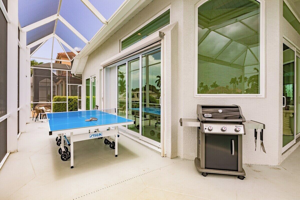En udendørs terrasse med et pingpongbord og en grill.