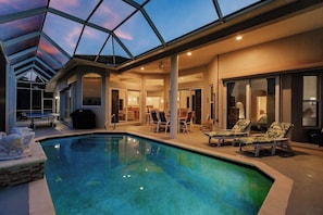 A swimming pool with lounge chairs and a covered patio area.