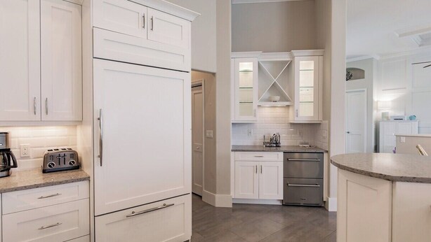 A modern kitchen with white cabinetry, a built-in oven, and a countertop with a toaster.