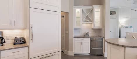 Una cocina moderna con armarios blancos, horno empotrado y encimera con un tostador.