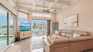 A spacious living room with a large beige sectional sofa, a flat-screen TV, and a ceiling fan.