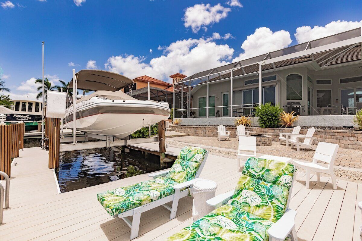 A marina with a boat docked, a pool area with lounge chairs, and a building with large windows.