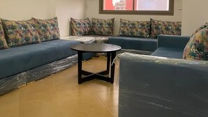 Un salon moderne avec un canapé bleu, une table basse ronde et un lustre décoratif.