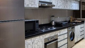 Een moderne keuken met een roestvrijstalen koelkast, een magnetron, een kookplaat en een wasmachine.