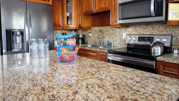 A kitchen with granite countertops, stainless steel appliances, wooden cabinets, and a stainless steel refrigerator.