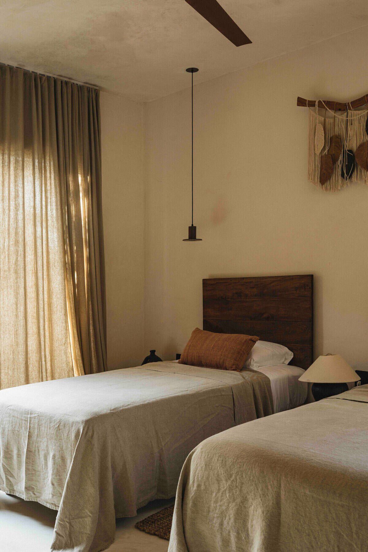 Ein Zimmer mit zwei Betten, einer Hängelampe und einer Wanddekoration aus Makramee.