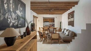 A modern living room with a wooden ceiling, a dining area, and a kitchen in the background. - 3BR Home in Gated Community | Rooftop Plunge Pool, Grill & Shared Poo (Tulum)