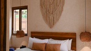 A bedroom with a wooden bed, a macrame wall hanging, a ceiling fan, and a window with a view of greenery. - 3BR Home in Gated Community | Rooftop Plunge Pool, Grill & Shared Poo (Tulum)