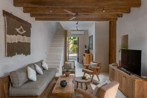 Relax in this stylish living room with a sofa, coffee table, and TV, surrounded by a large window offering a view of the outdoors.