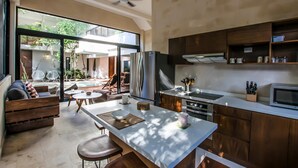 A modern kitchen with a large island, built-in appliances, and a view to an outdoor patio. - Casa Kookay | 6BR Luxury Villa w/ 3 Pools | Aldea Zama, Tulum (Tulum)