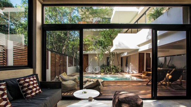 A modern outdoor living area with a pool, a sofa, a coffee table, and lounge chairs. - Casa Kookay | 6BR Luxury Villa w/ 3 Pools | Aldea Zama, Tulum (Tulum)