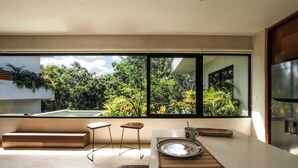 A modern kitchen with a large window, a built-in bench, and a minimalist design. - Casa Kookay | 6BR Luxury Villa w/ 3 Pools | Aldea Zama, Tulum (Tulum)
