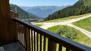 Ein Holzbalkon mit Blick auf ein Tal, Berge und eine in der Ferne liegende Stadt.