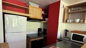 Eine kleine Küche mit Kühlschrank, Mikrowelle, Spüle und Holzschränken.