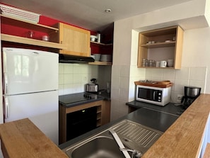 Une cuisine compacte équipée d’un réfrigérateur, d’une cuisinière, d’un four à micro-ondes et d’un évier.