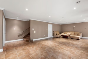 Uma sala de estar espaçosa com um sofá bege, uma mesa de centro e uma escada que leva a outro andar.