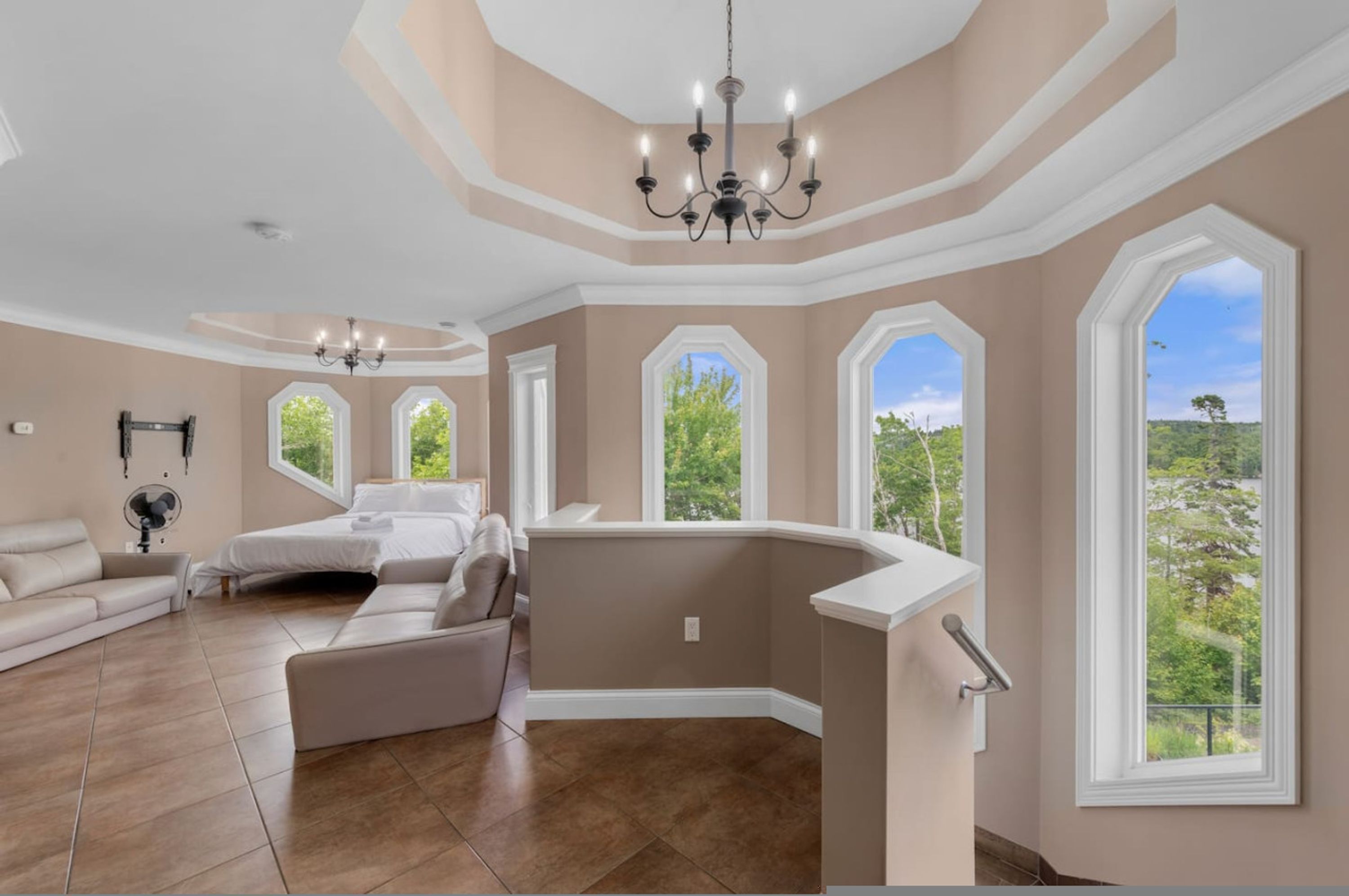 A spacious living room with a large window, a chandelier, and a modern sofa.