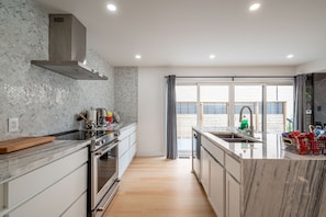 Uma cozinha moderna com ilha central, eletrodomésticos de aço inoxidável e um backsplash em padrão herringbone.