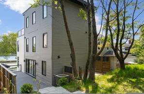 Um edifício moderno de dois andares com telhado plano, janelas amplas e uma área de deck.