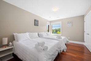 A hotel room with two beds, a nightstand, a lamp, and two wall signs. - Serene Modern Lakehouse on Golf Course (Hammonds Plains)