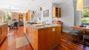 A modern kitchen with wooden cabinets, a central island, and a dining area with bar stools.