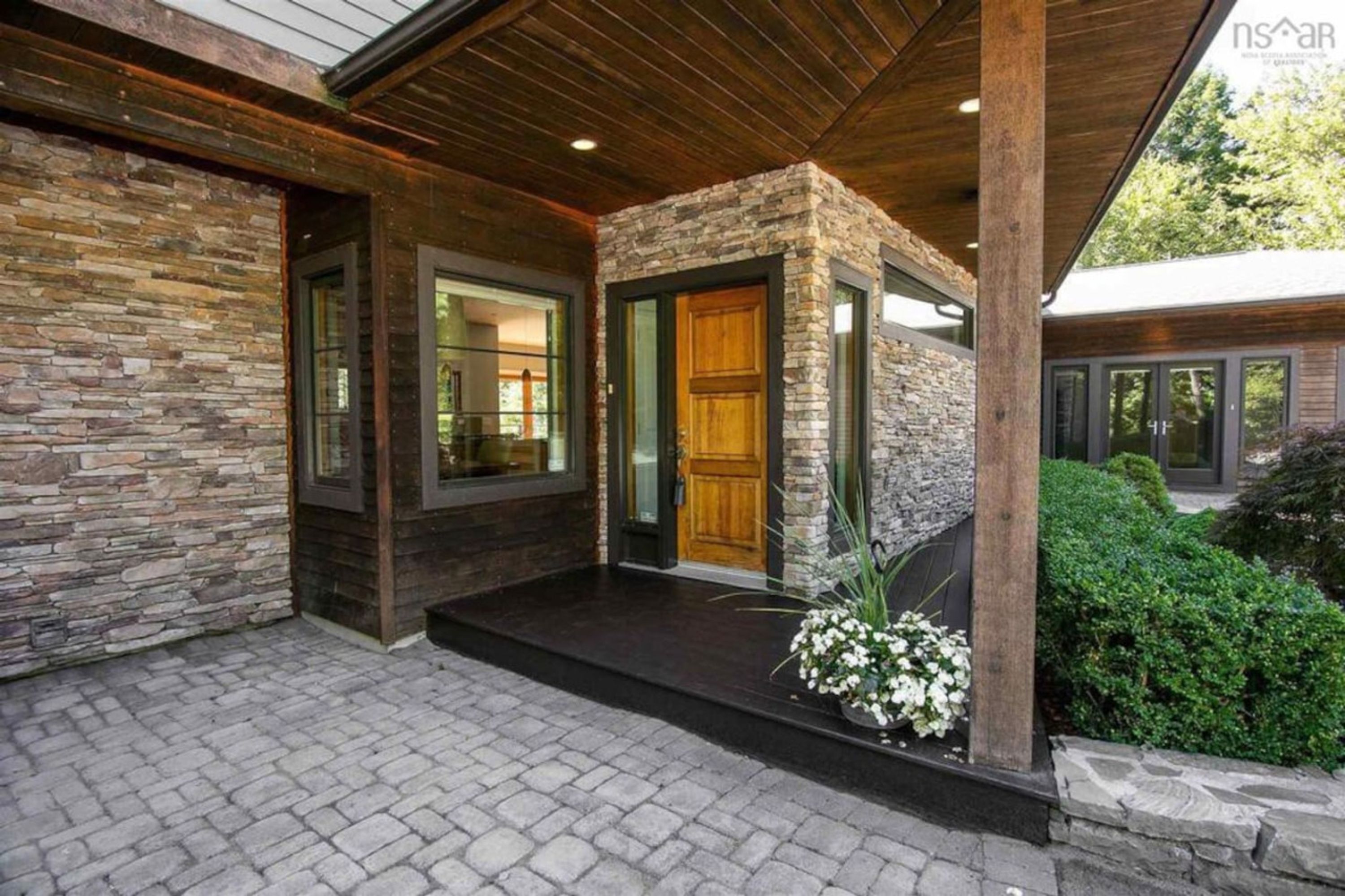A modern house with a stone facade, large windows, and a wooden door.