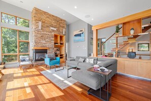 Una sala de estar moderna con chimenea de piedra, un sofá gris y un sillón azul.