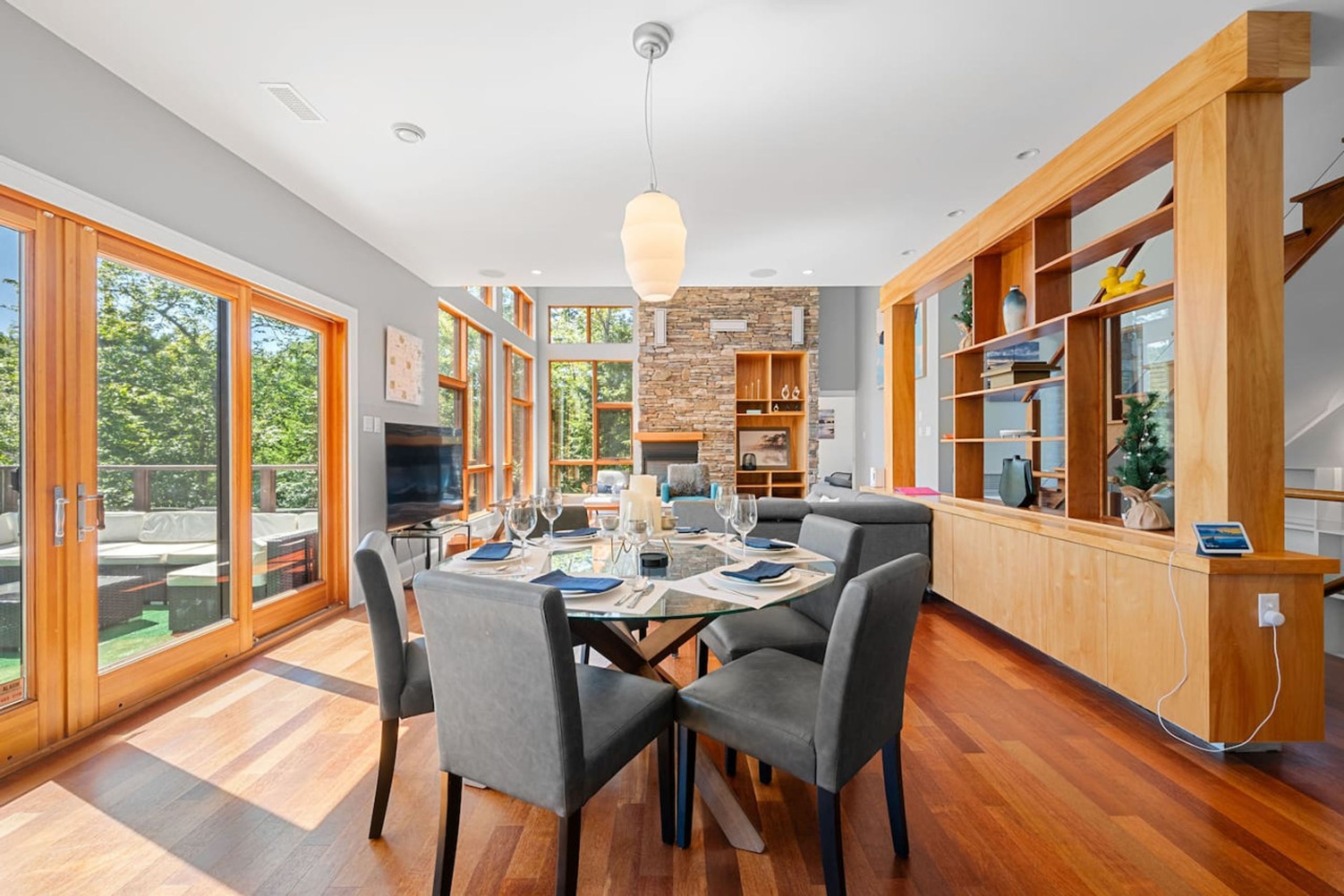 A modern kitchen with a dining area, large windows, and a stone accent wall.