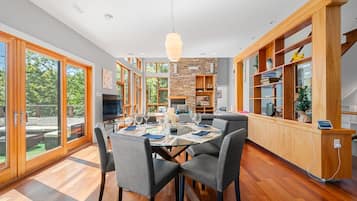 A modern kitchen with a dining area, large windows, and a stone accent wall.