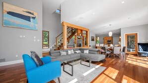 A modern living room with a sectional sofa, a glass coffee table, and a staircase leading to an upper level.
