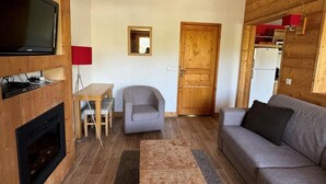 A cozy living room with a fireplace, a sofa, a small table, and a chair. - Ski-in/ski-out & foot of the slopes, 7th floor, view ski slopes, swimming pool, balcony, tv (La Plagne)