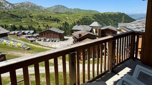 A balcony with a view of a mountainous landscape, including buildings and a ski lift. - Ski-in/ski-out & foot of the slopes, 7th floor, view ski slopes, swimming pool, balcony, tv (La Plagne)