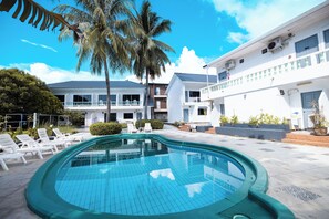 A swimming pool with lounge chairs, a palm tree, and a building with balconies. - The Coconut Resort Hotel (Patong)