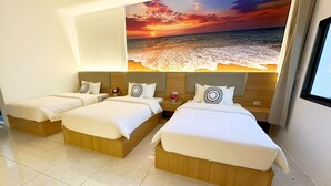 Habitación de hotel con dos camas, un mural grande de una puesta de sol sobre el océano y una ventana con cortinas.