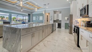 Een moderne keuken met marmeren werkbladen, roestvrijstalen apparatuur en een groot eiland.