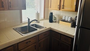 A kitchen with wooden cabinets, a stainless steel sink, a coffee maker, and a refrigerator. - Cozy loft in Gardiner with AC, WiFi and splendid views  (Gardiner)