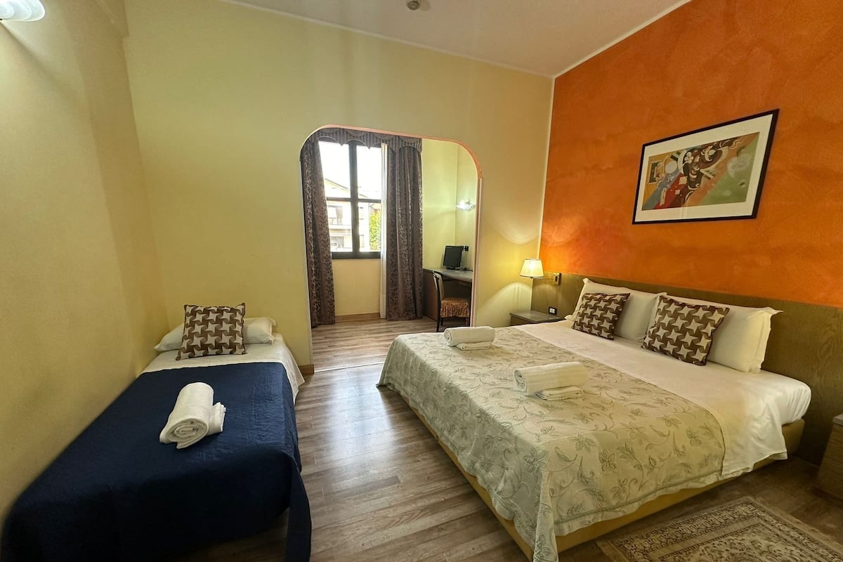 A hotel room with two beds, a desk, and a chair.