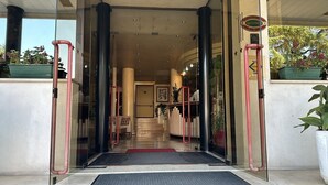 Ein Hotel Eingang mit Glastür, einer Rezeption und einer Treppe, die nach innen führt.