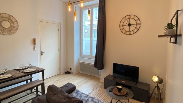 Een moderne woonkamer met een bank, televisie en een eethoek.