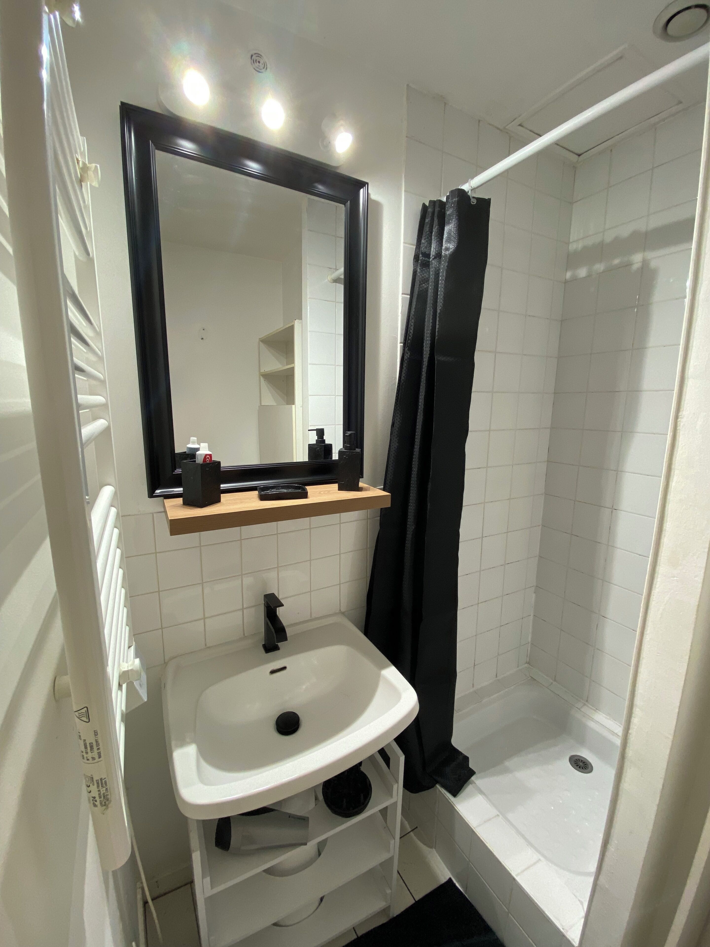 A bathroom with a white sink, a mirror, a shower, and a towel rack.