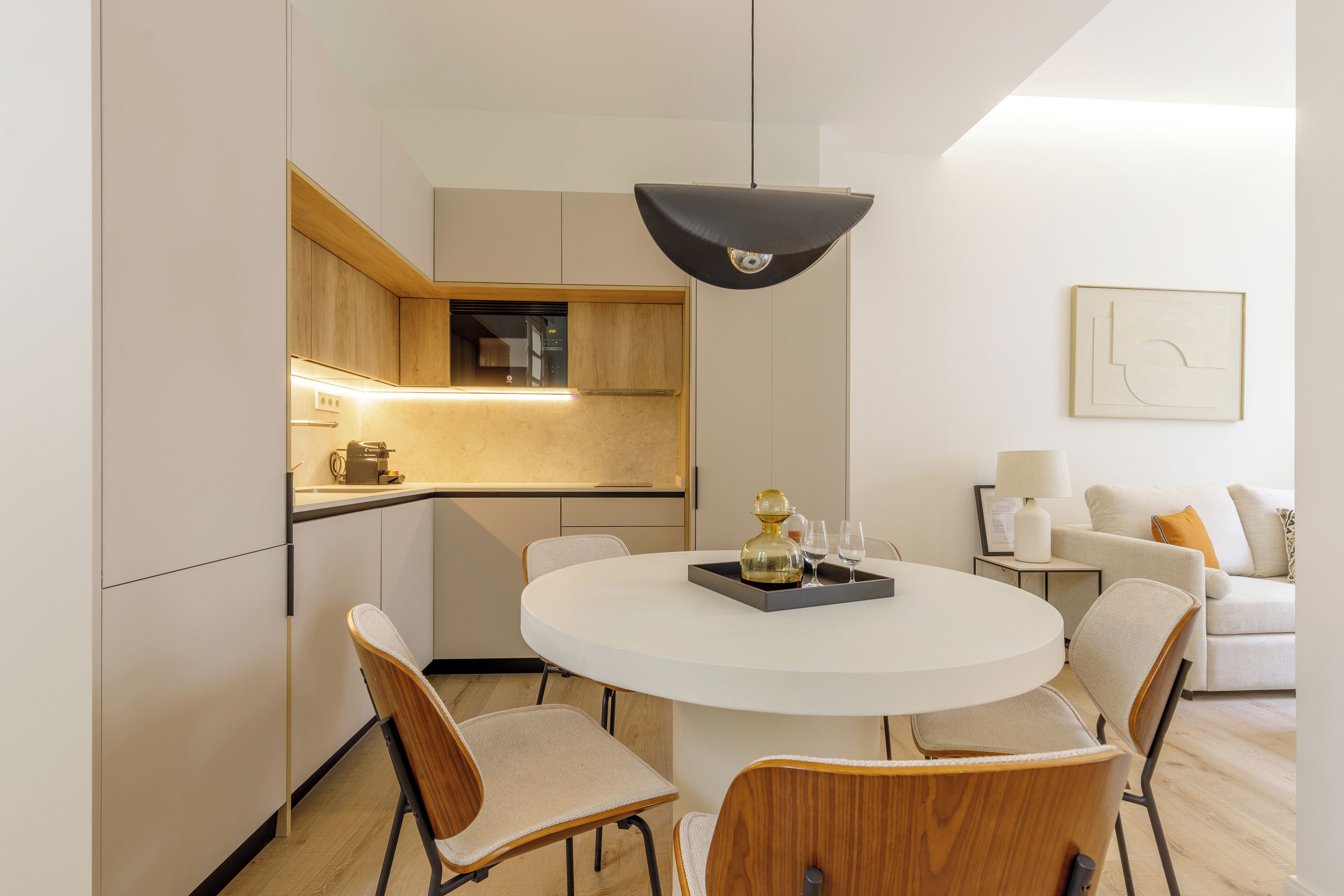 Een moderne eetruimte met een ronde tafel, stoelen en een hanglamp.