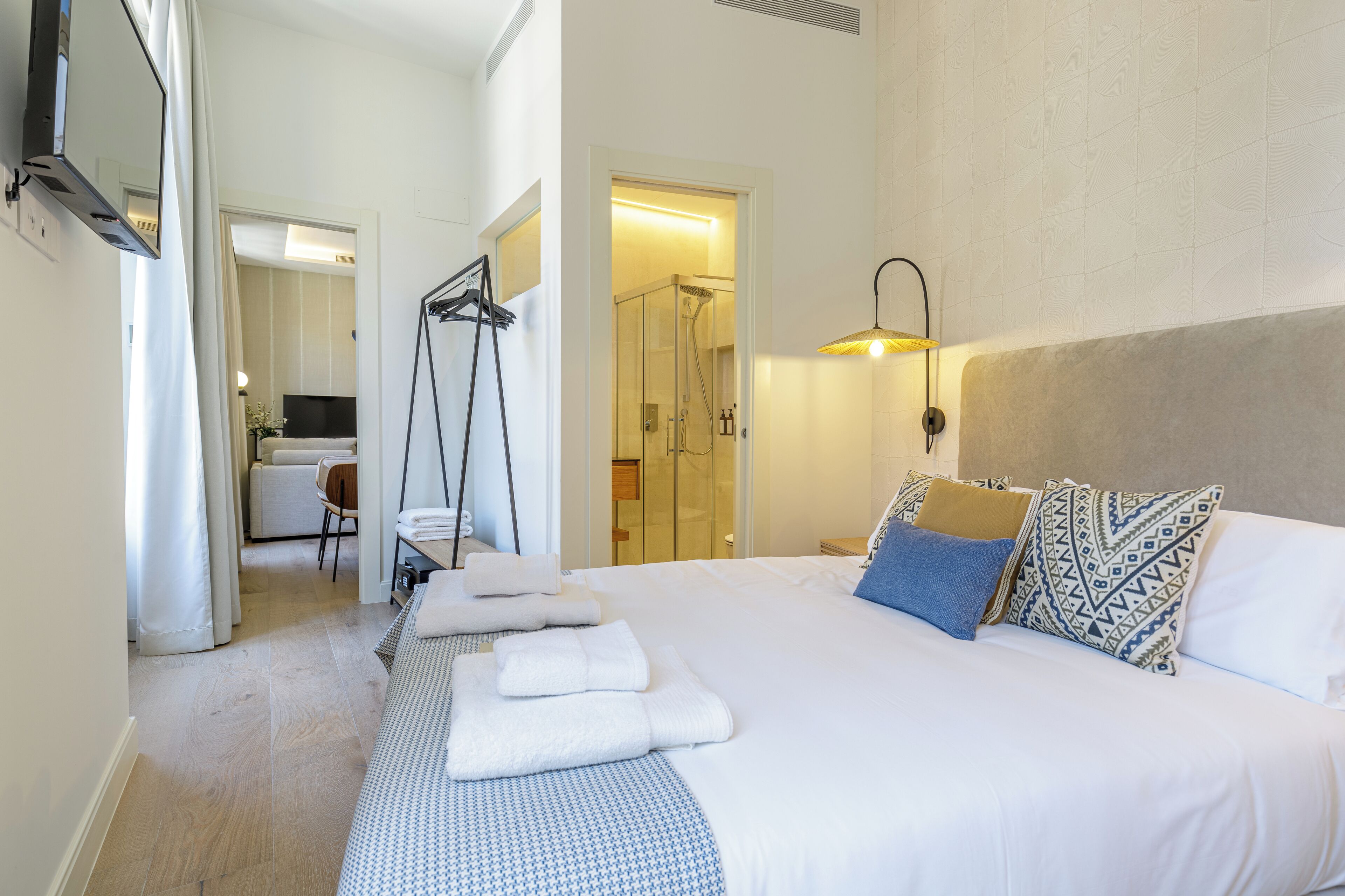 A hotel room with a large bed, a shower area, a desk, and a TV mounted on the wall.