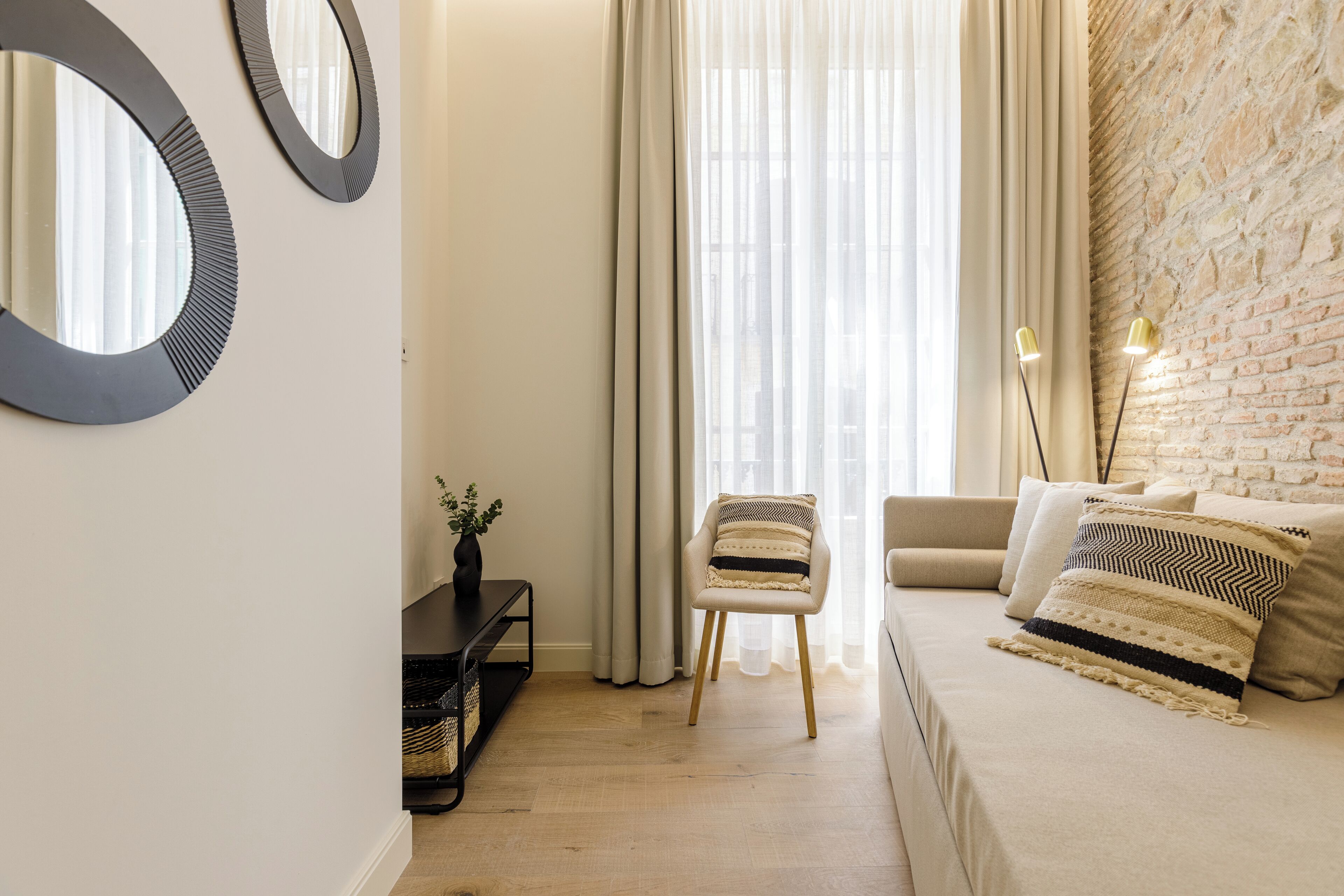 Una sala de estar moderna con un sofá, un sillón, una mesita de centro y un espejo de pared.